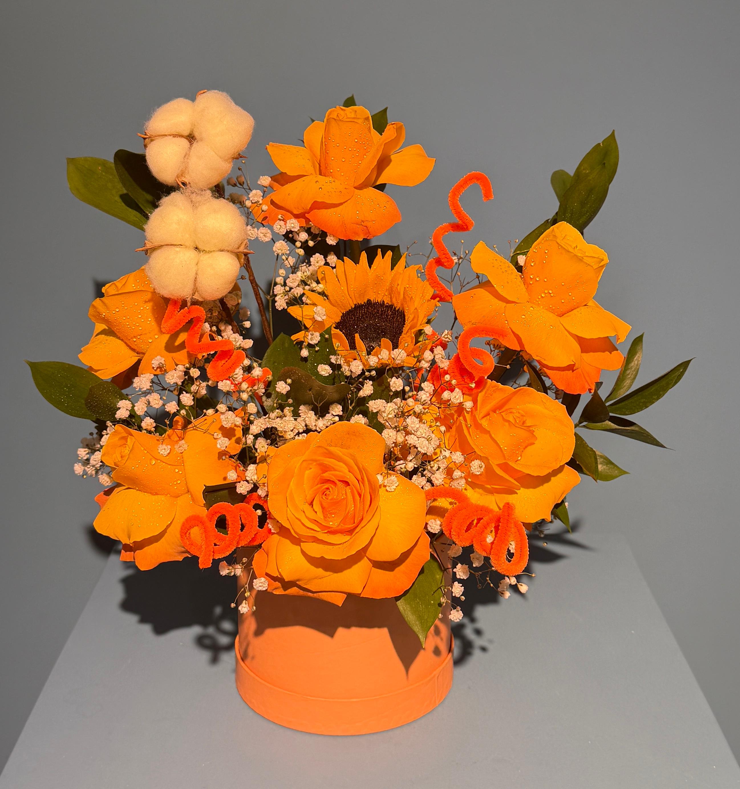 Desert Sunrise orange rose hat box arrangement with sunflower cotton and spiral noodle accents